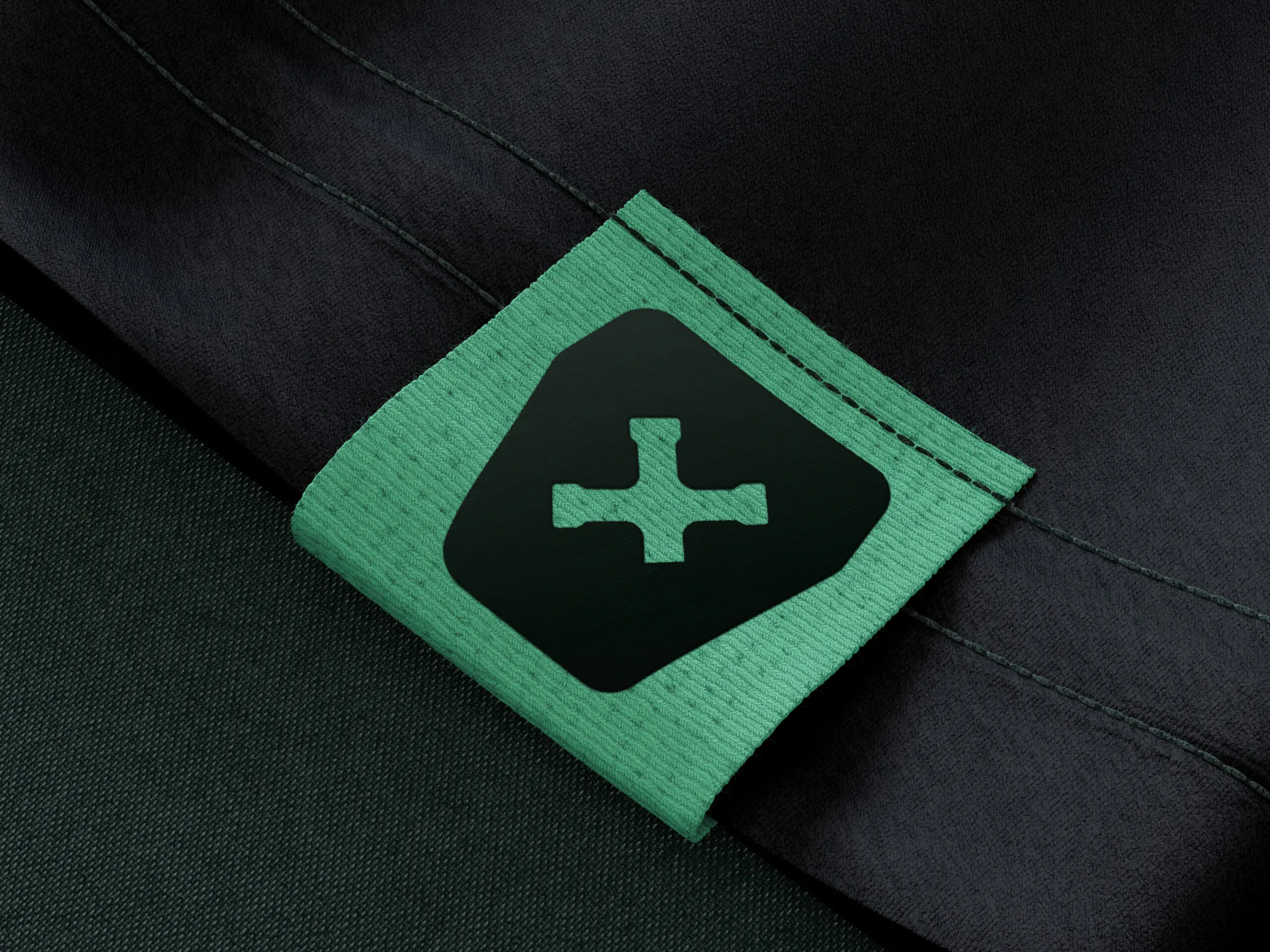 Auf dunkle Kleidung ist ein grünes Stoffetikett mit einem schwarzen, kreuzförmigen Symbol aufgenäht.