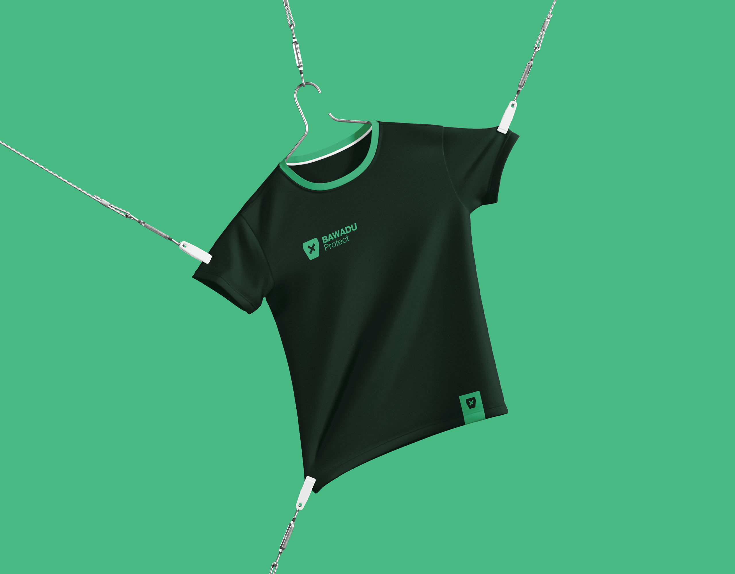 Ein schwarzes T-Shirt mit grüner Einfassung hängt an einem Kleiderbügel, der an Drähten befestigt ist. Auf dem Shirt sind ein Logo und der Schriftzug „CanadaU Forward“ zu sehen. Der Hintergrund ist einfarbig grün.
